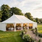 White wedding marquee hire set up on a lawn surrounded by lush gardens and trees